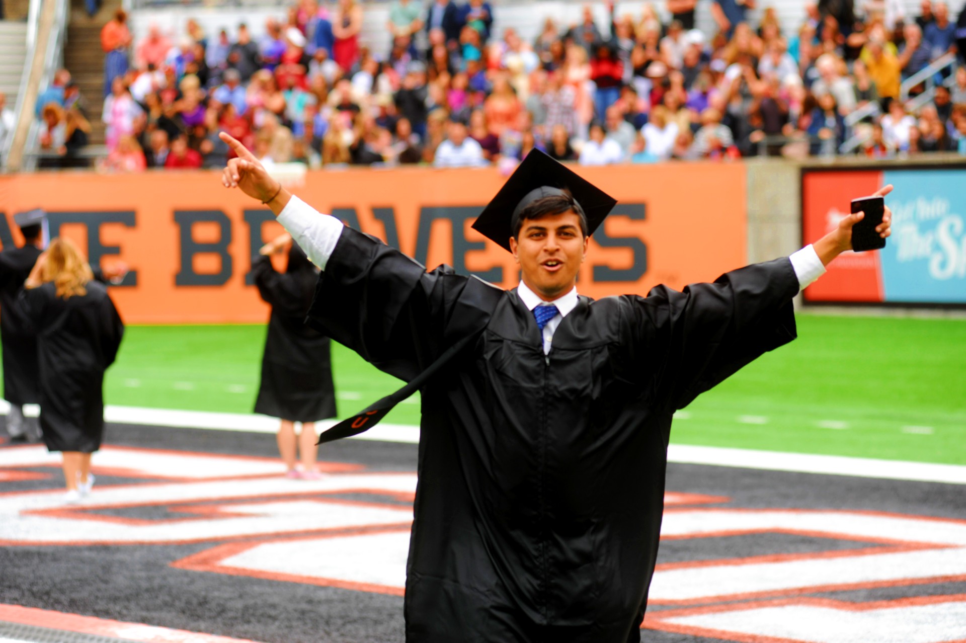 graduate with arms raised at commencement