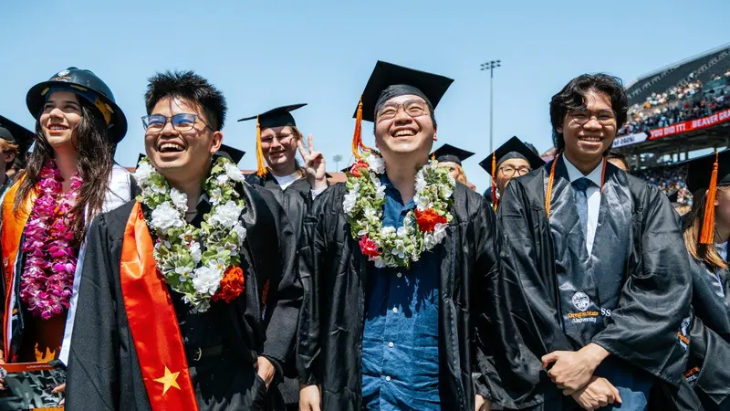 graduates standing and smiling during commencement