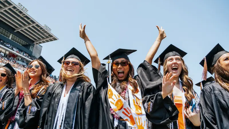Graduates standing and cheering during commencement